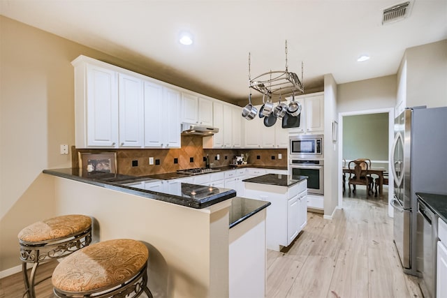 13330 Via Torre De Pisa Ln, Cypress, TX 77429 - kitchen with appliances with stainless steel finishes, light wood-style floors, a peninsula, decorative backsplash, and recessed lighting
