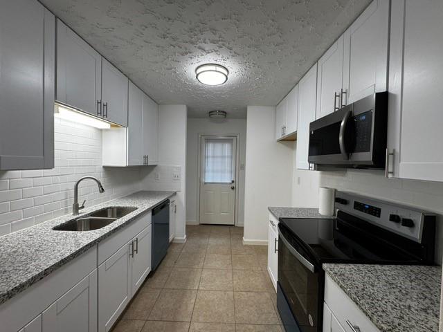 16310 Meadowbrook Farm Rd, Houston, TX 77082 - kitchen featuring appliances with stainless steel finishes, white cabinets, light stone countertops, and a textured ceiling