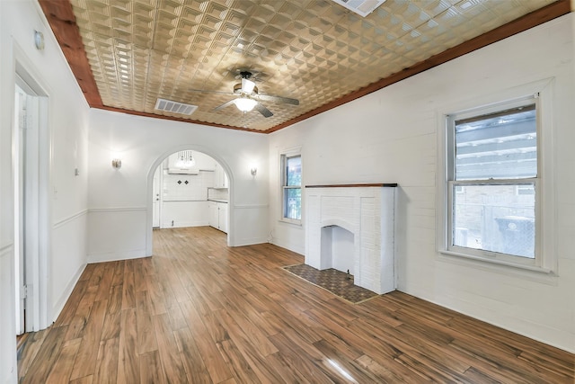 702 Caplin St, Houston, TX 77022 - unfurnished living room with a ceiling fan, arched walkways, wood finished floors, ornamental molding, and a fireplace