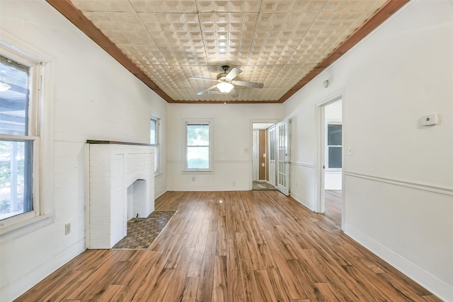 702 Caplin St, Houston, TX 77022 - unfurnished living room featuring a ceiling fan, wood finished floors, an ornate ceiling, ornamental molding, and a brick fireplace