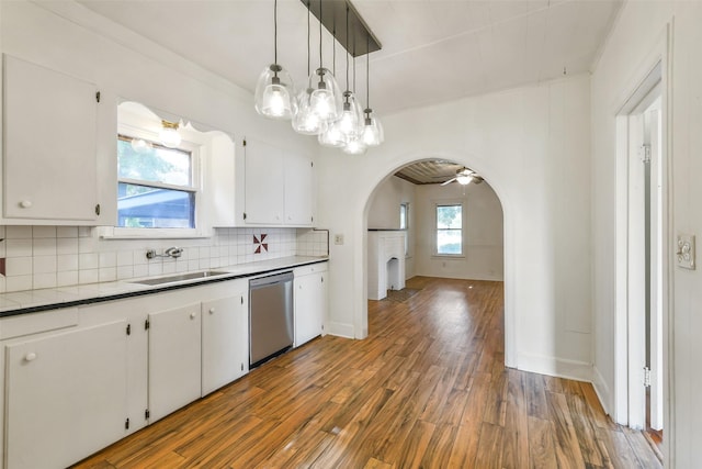 702 Caplin St, Houston, TX 77022 - kitchen featuring stainless steel dishwasher, arched walkways, wood finished floors, white cabinets, and tasteful backsplash