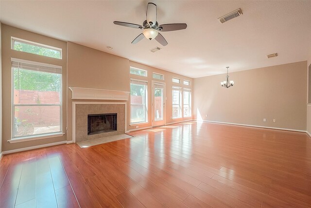 7210 Welshwood Ln, Sugar Land, TX 77479 - unfurnished living room featuring a chandelier, a ceiling fan, a fireplace, and light wood-type flooring