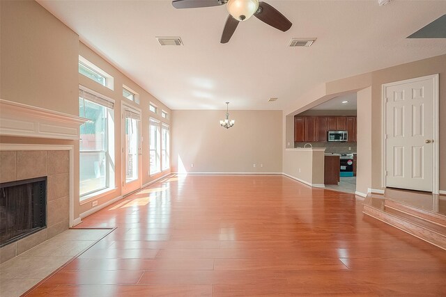 7210 Welshwood Ln, Sugar Land, TX 77479 - unfurnished living room featuring a fireplace, light wood-type flooring, a chandelier, and ceiling fan