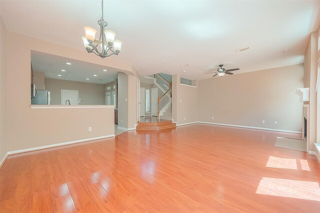 7210 Welshwood Ln, Sugar Land, TX 77479 - unfurnished living room featuring light wood-style floors, stairs, a ceiling fan, a chandelier, and recessed lighting