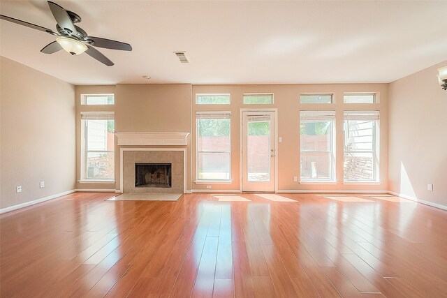 7210 Welshwood Ln, Sugar Land, TX 77479 - unfurnished living room with a tiled fireplace, ceiling fan, and light wood-style flooring