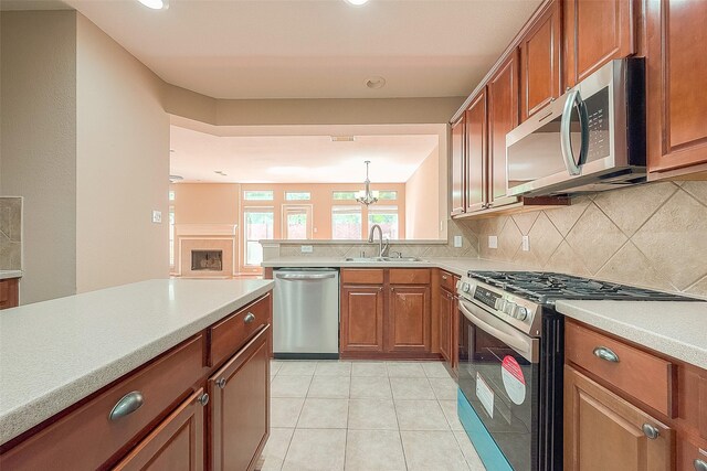 7210 Welshwood Ln, Sugar Land, TX 77479 - kitchen with stainless steel appliances, brown cabinets, decorative backsplash, light countertops, and a chandelier