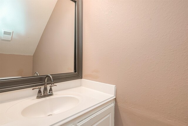 7210 Welshwood Ln, Sugar Land, TX 77479 - bathroom featuring vanity, a textured wall, and lofted ceiling