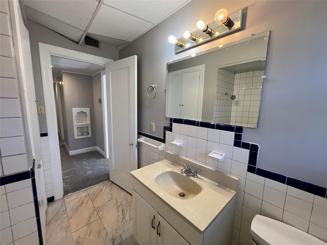 4905 Jackson St, Houston, TX 77004 - bathroom with vanity, marble finish flooring, a wainscoted wall, tile walls, and a drop ceiling