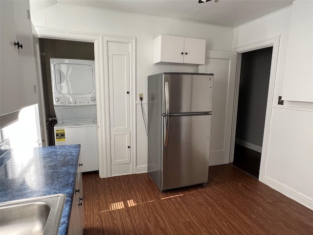 4905 Jackson St, Houston, TX 77004 - kitchen featuring freestanding refrigerator, stacked washer and clothes dryer, dark wood finished floors, white cabinets, and dark countertops