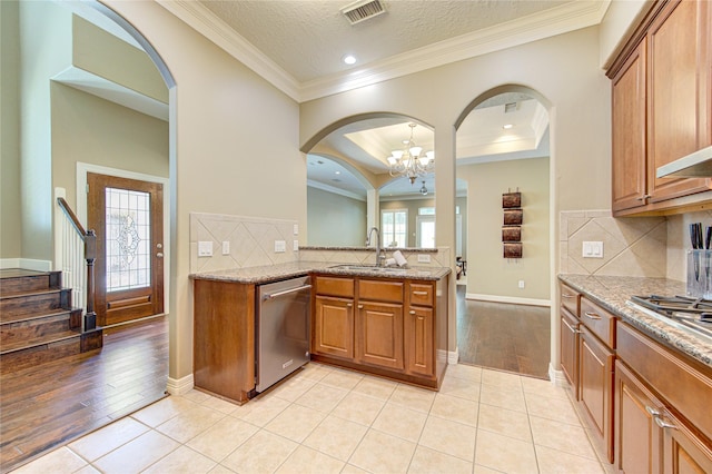 1415 Baldwin Square Ln, Houston, TX 77077 - kitchen with stainless steel appliances, brown cabinetry, light stone countertops, decorative backsplash, and a chandelier