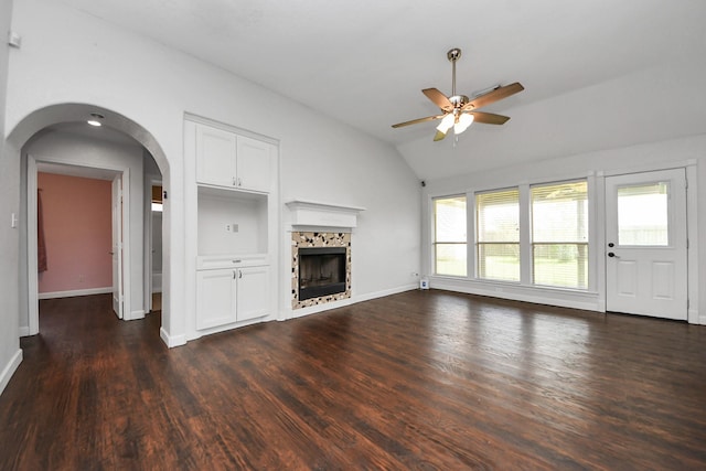 204 Audubon Woods Ct, Richwood, TX 77531 - unfurnished living room with lofted ceiling, a ceiling fan, dark wood-type flooring, a fireplace, and arched walkways