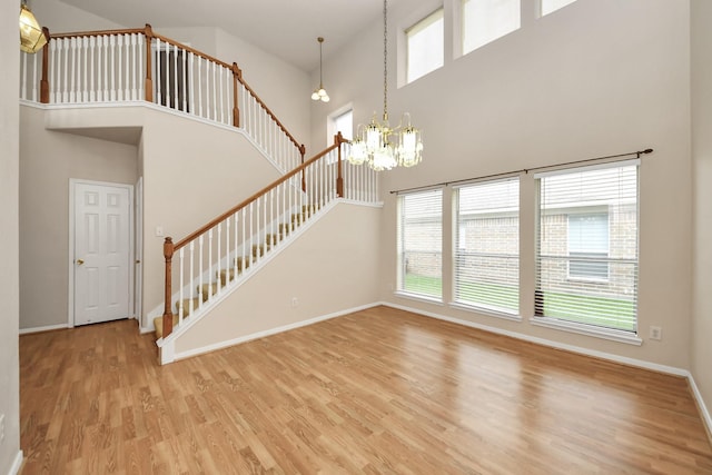 24219 Camillia Ridge Way, Katy, TX 77493 - unfurnished living room with a high ceiling, stairway, healthy amount of natural light, a chandelier, and light wood-type flooring