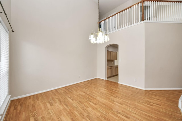 24219 Camillia Ridge Way, Katy, TX 77493 - unfurnished dining area with a towering ceiling, arched walkways, light wood-type flooring, and a chandelier