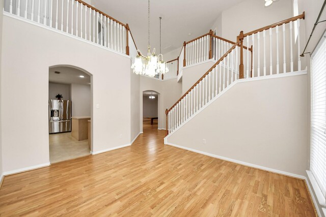 24219 Camillia Ridge Way, Katy, TX 77493 - empty room with arched walkways, wood finished floors, a towering ceiling, and a chandelier