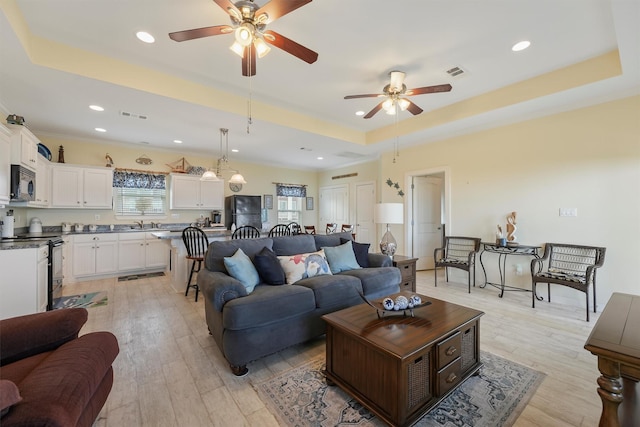 2577 Holiday Dr, Crystal Beach, TX 77650 - living room with a tray ceiling, a ceiling fan, recessed lighting, and light wood-style floors