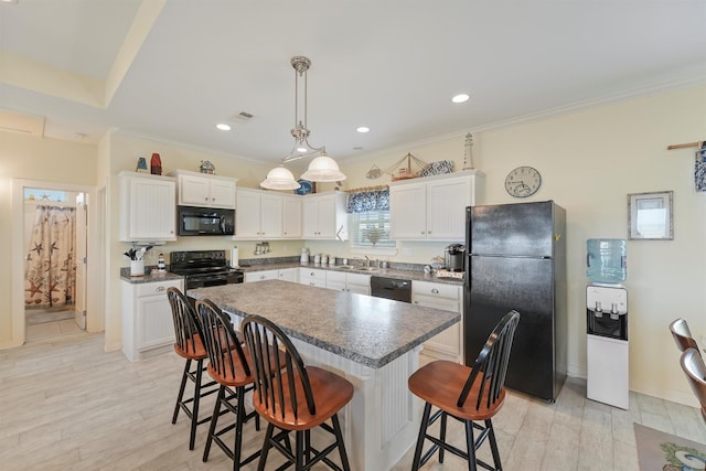 2577 Holiday Dr, Crystal Beach, TX 77650 - kitchen featuring black appliances, a kitchen bar, a kitchen island, white cabinetry, and crown molding