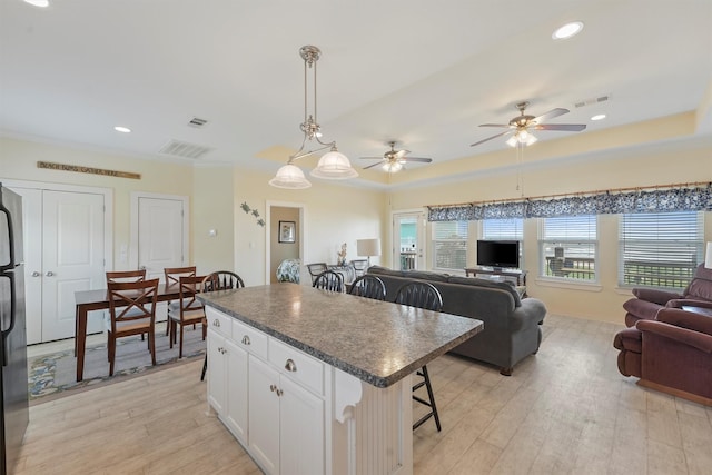 2577 Holiday Dr, Crystal Beach, TX 77650 - kitchen featuring a breakfast bar, dark countertops, freestanding refrigerator, light wood-style flooring, and open floor plan