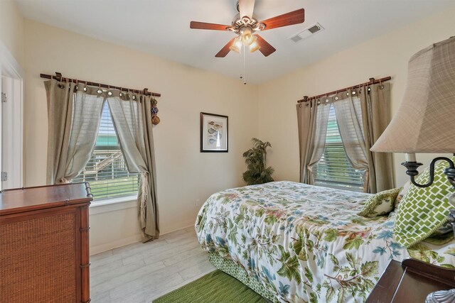 2577 Holiday Dr, Crystal Beach, TX 77650 - bedroom with multiple windows, light wood-style floors, and ceiling fan