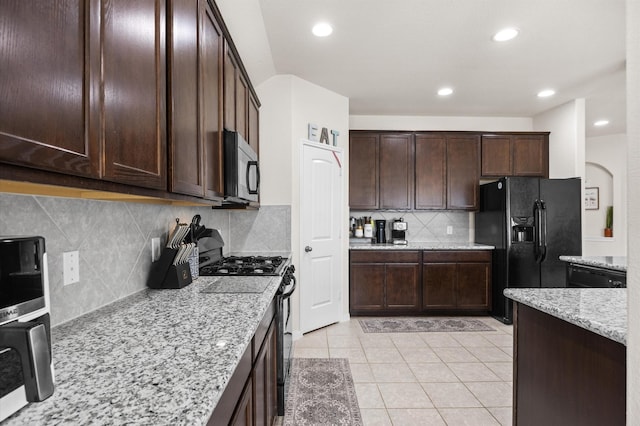9127 Sasson Blvd, Houston, TX 77044 - kitchen with black appliances, light stone countertops, decorative backsplash, dark brown cabinets, and light tile patterned floors