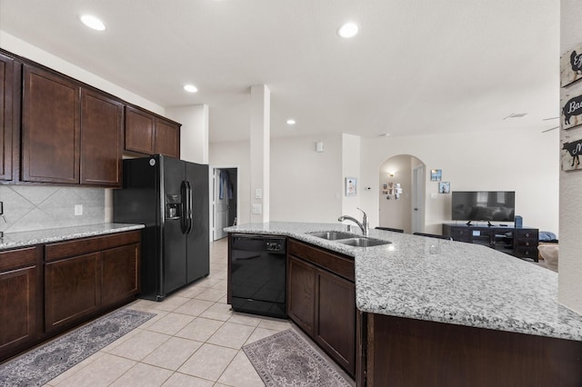 9127 Sasson Blvd, Houston, TX 77044 - kitchen with black appliances, arched walkways, dark brown cabinetry, light tile patterned floors, and light stone counters