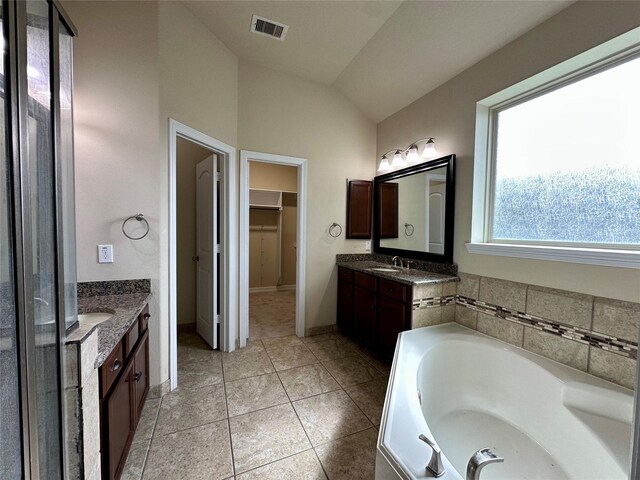22411 Limestone Crest Ln, Katy, TX 77449 - full bath featuring two vanities, lofted ceiling, a bath, a walk in closet, and tile patterned flooring