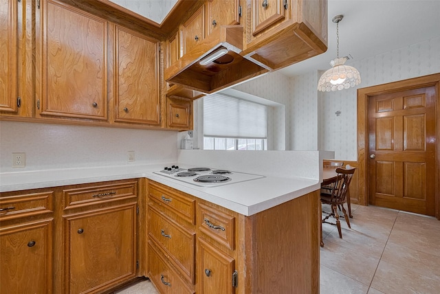 17718 Terrawren Ln, Spring, TX 77379 - kitchen featuring wallpapered walls, white electric stovetop, a peninsula, brown cabinets, and light countertops
