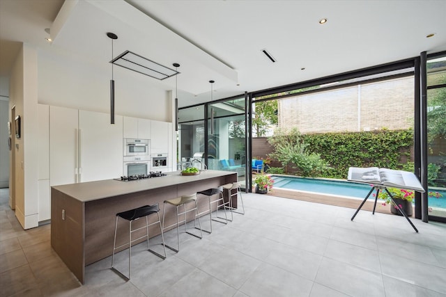 2332 Wroxton Rd, Houston, TX 77005 - kitchen featuring floor to ceiling windows, plenty of natural light, white cabinets, modern cabinets, and a breakfast bar area