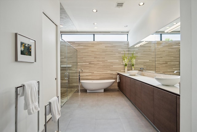 2332 Wroxton Rd, Houston, TX 77005 - bathroom with double vanity, tile walls, a freestanding bath, recessed lighting, and a stall shower