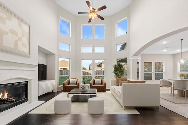 2131 Acadian Way, Brookshire, TX 77423 - living area with ceiling fan, a high ceiling, arched walkways, hardwood / wood-style flooring, and a premium fireplace