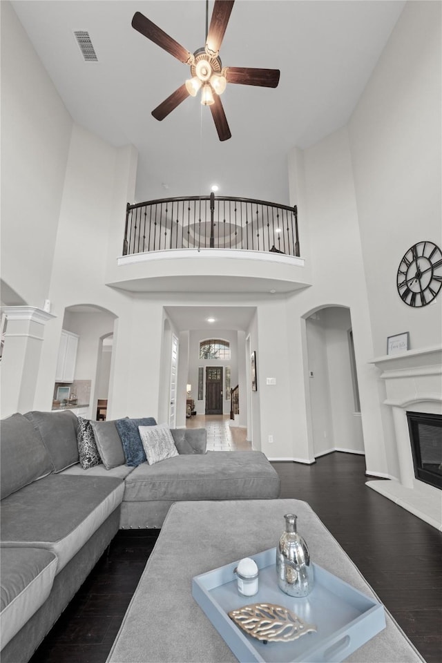 2131 Acadian Way, Brookshire, TX 77423 - living room with arched walkways, dark wood-type flooring, a towering ceiling, a glass covered fireplace, and ceiling fan