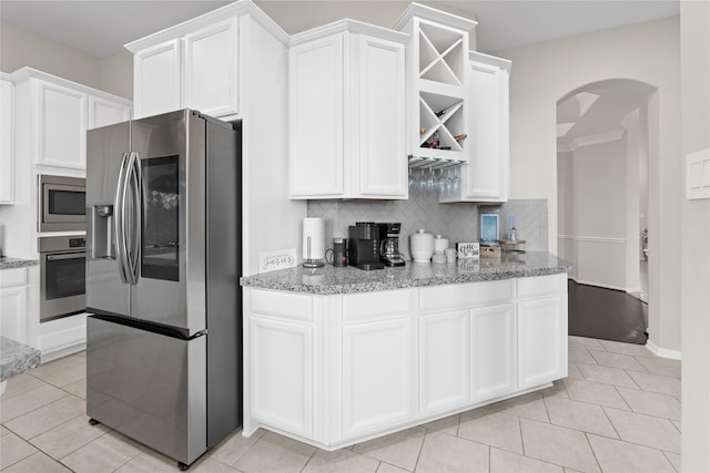 2131 Acadian Way, Brookshire, TX 77423 - kitchen featuring stainless steel appliances, arched walkways, backsplash, and white cabinetry