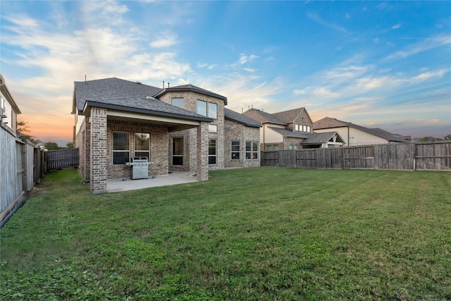 2131 Acadian Way, Brookshire, TX 77423 - back of house at dusk with brick siding, a patio area, a fenced backyard, and roof with shingles