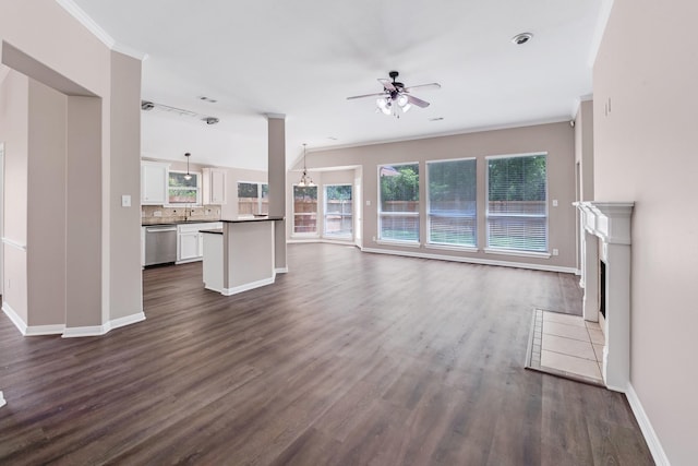 461 Cumberland Trl, Conroe, TX 77302 - unfurnished living room featuring ceiling fan, plenty of natural light, dark wood-style floors, a tiled fireplace, and ornamental molding