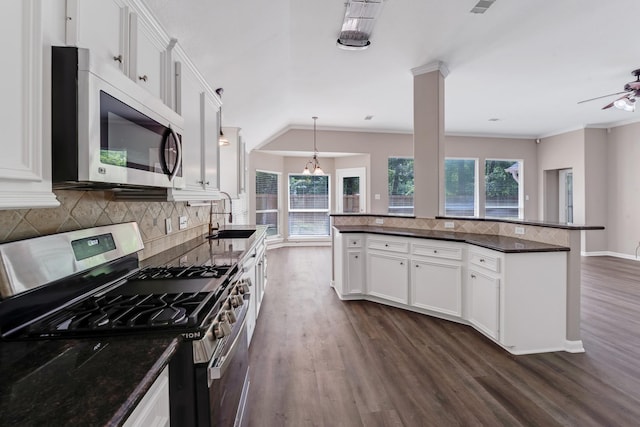 461 Cumberland Trl, Conroe, TX 77302 - kitchen featuring appliances with stainless steel finishes, dark wood finished floors, backsplash, white cabinetry, and decorative light fixtures