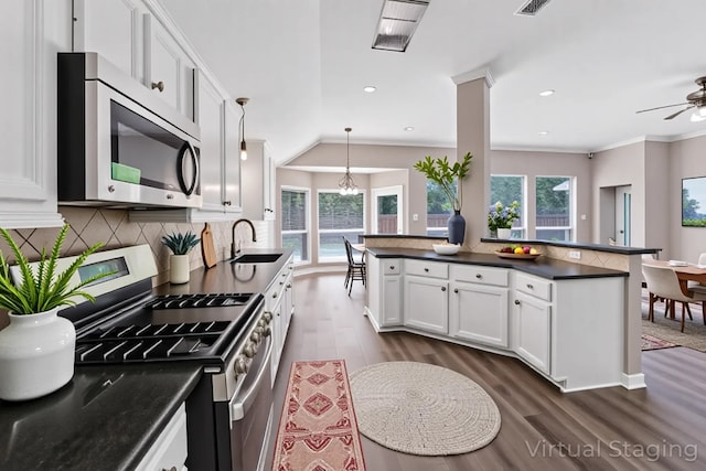461 Cumberland Trl, Conroe, TX 77302 - kitchen featuring appliances with stainless steel finishes, dark countertops, dark wood-style floors, healthy amount of natural light, and ornamental molding
