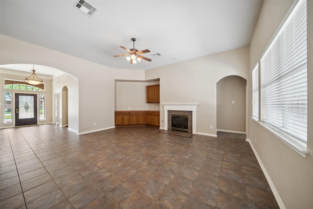 15331 Springhill Bend Ln, Cypress, TX 77429 - unfurnished living room featuring a ceiling fan, plenty of natural light, arched walkways, and a glass covered fireplace
