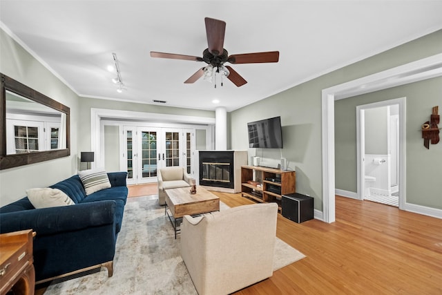1621 Cherryhurst St, Houston, TX 77006 - living area with french doors, ornamental molding, light wood-type flooring, ceiling fan, and a glass covered fireplace