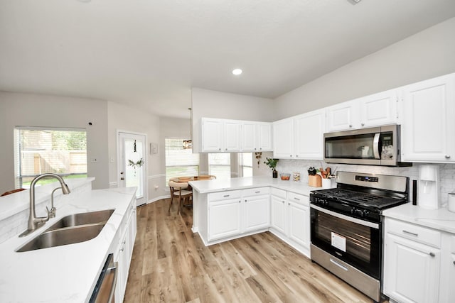 235 Cedar Elm Ln, Sugar Land, TX 77479 - kitchen featuring stainless steel appliances, decorative backsplash, a peninsula, light wood-style flooring, and healthy amount of natural light