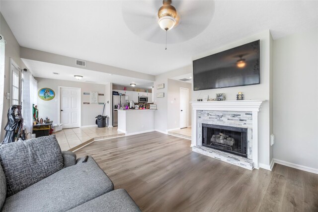 3825 Redbud Dr, La Porte, TX 77571 - living area featuring light wood-style flooring, ceiling fan, and a fireplace with raised hearth