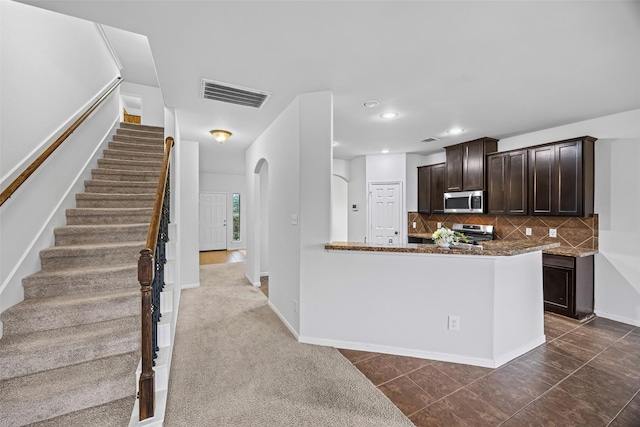 9203 Sasson Blvd, Houston, TX 77044 - kitchen with appliances with stainless steel finishes, dark brown cabinets, tasteful backsplash, dark stone countertops, and recessed lighting