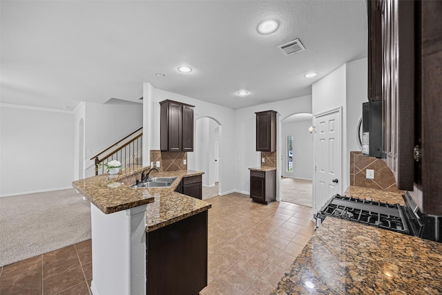 9203 Sasson Blvd, Houston, TX 77044 - kitchen featuring arched walkways, stainless steel microwave, dark brown cabinetry, a peninsula, and tasteful backsplash
