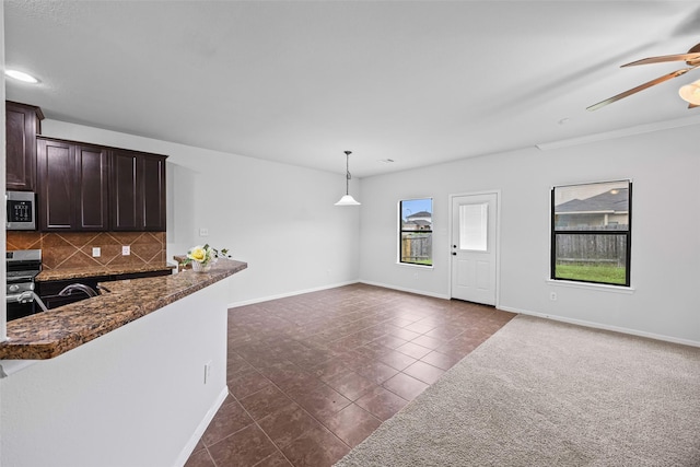 9203 Sasson Blvd, Houston, TX 77044 - kitchen featuring stainless steel microwave, dark brown cabinetry, ceiling fan, tasteful backsplash, and dark tile patterned flooring