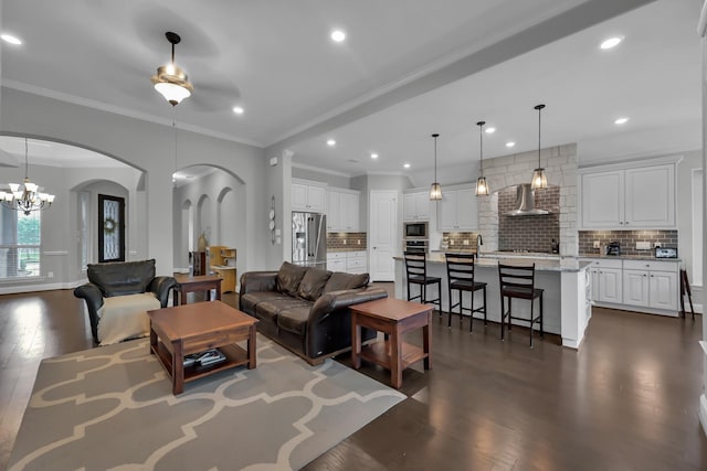 31268 New Forest Park Ln, Spring, TX 77386 - living room with arched walkways, dark wood-style flooring, a chandelier, crown molding, and a ceiling fan