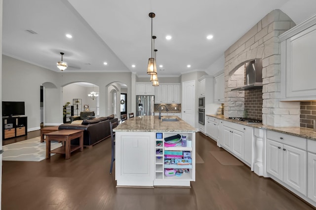 31268 New Forest Park Ln, Spring, TX 77386 - kitchen with wall chimney exhaust hood, arched walkways, appliances with stainless steel finishes, dark wood-type flooring, and open floor plan