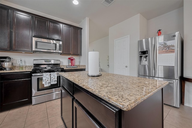 5830 Acacia Rose Ct, Richmond, TX 77407 - kitchen with stainless steel appliances, light tile patterned floors, a center island, light stone counters, and dark brown cabinets