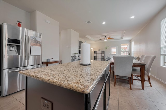 5830 Acacia Rose Ct, Richmond, TX 77407 - kitchen with stainless steel refrigerator with ice dispenser, a tray ceiling, a center island, light tile patterned floors, and light stone counters