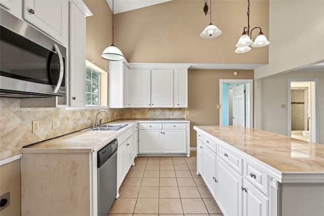 119 8th St, San Leon, TX 77539 - kitchen featuring appliances with stainless steel finishes, high vaulted ceiling, light countertops, decorative backsplash, and white cabinets