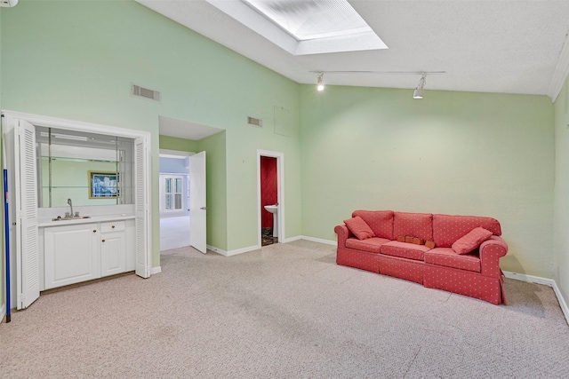12 E Dansby Dr, Galveston, TX 77551 - sitting room featuring rail lighting, light colored carpet, a skylight, and high vaulted ceiling