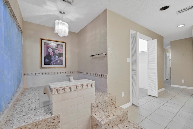 12 E Dansby Dr, Galveston, TX 77551 - bathroom with tile patterned flooring, a chandelier, a textured ceiling, a closet, and a tub to relax in