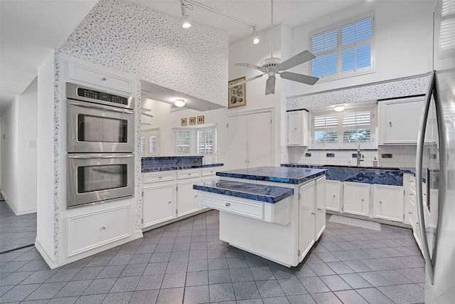 12 E Dansby Dr, Galveston, TX 77551 - kitchen with stainless steel appliances, dark countertops, ceiling fan, white cabinetry, and dark tile patterned flooring